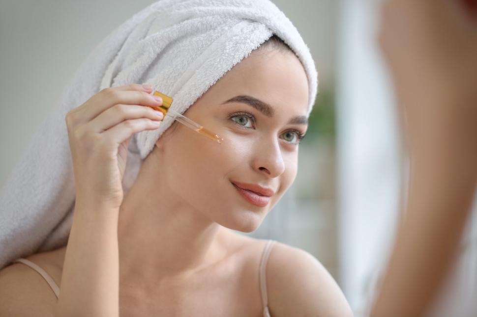 a woman applying a dropper on her face